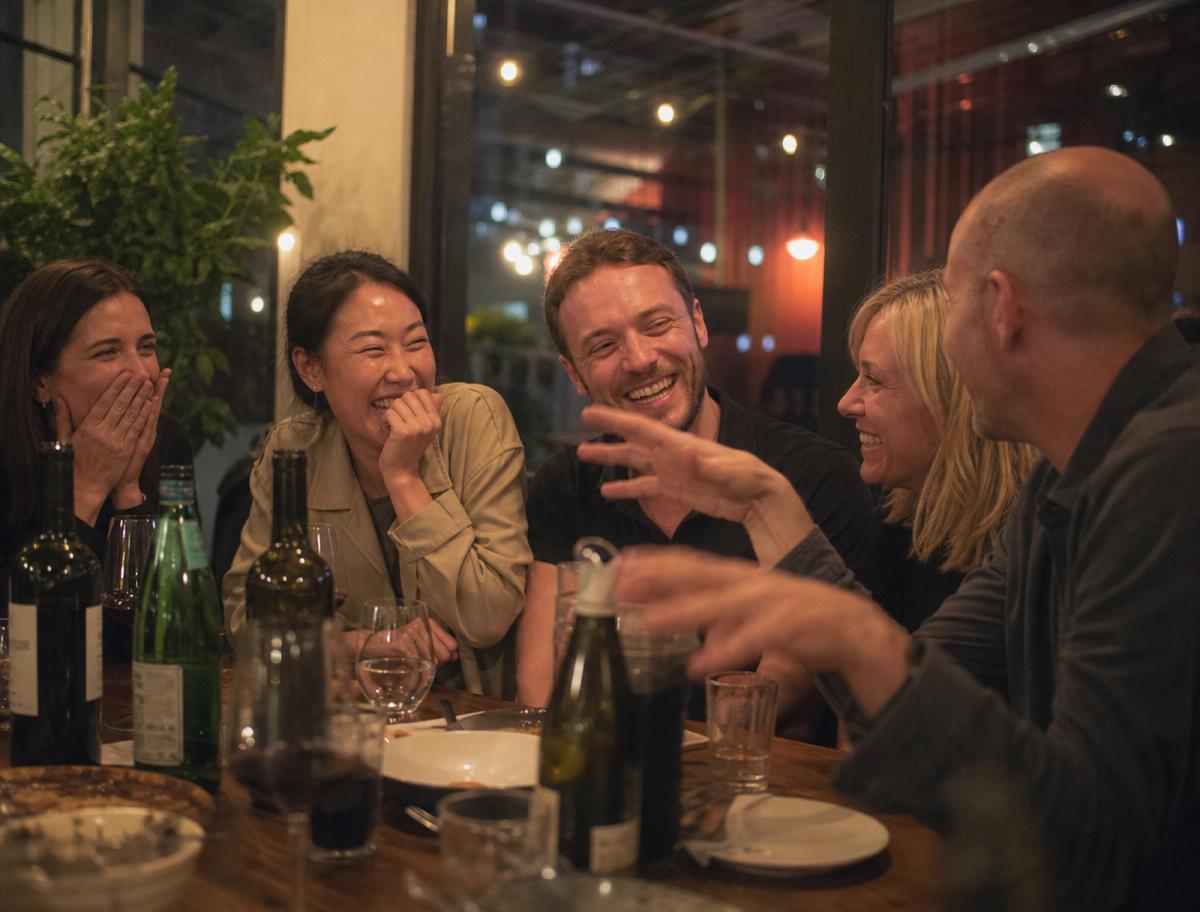 A small group of friends laughing together over a candlelit dinner